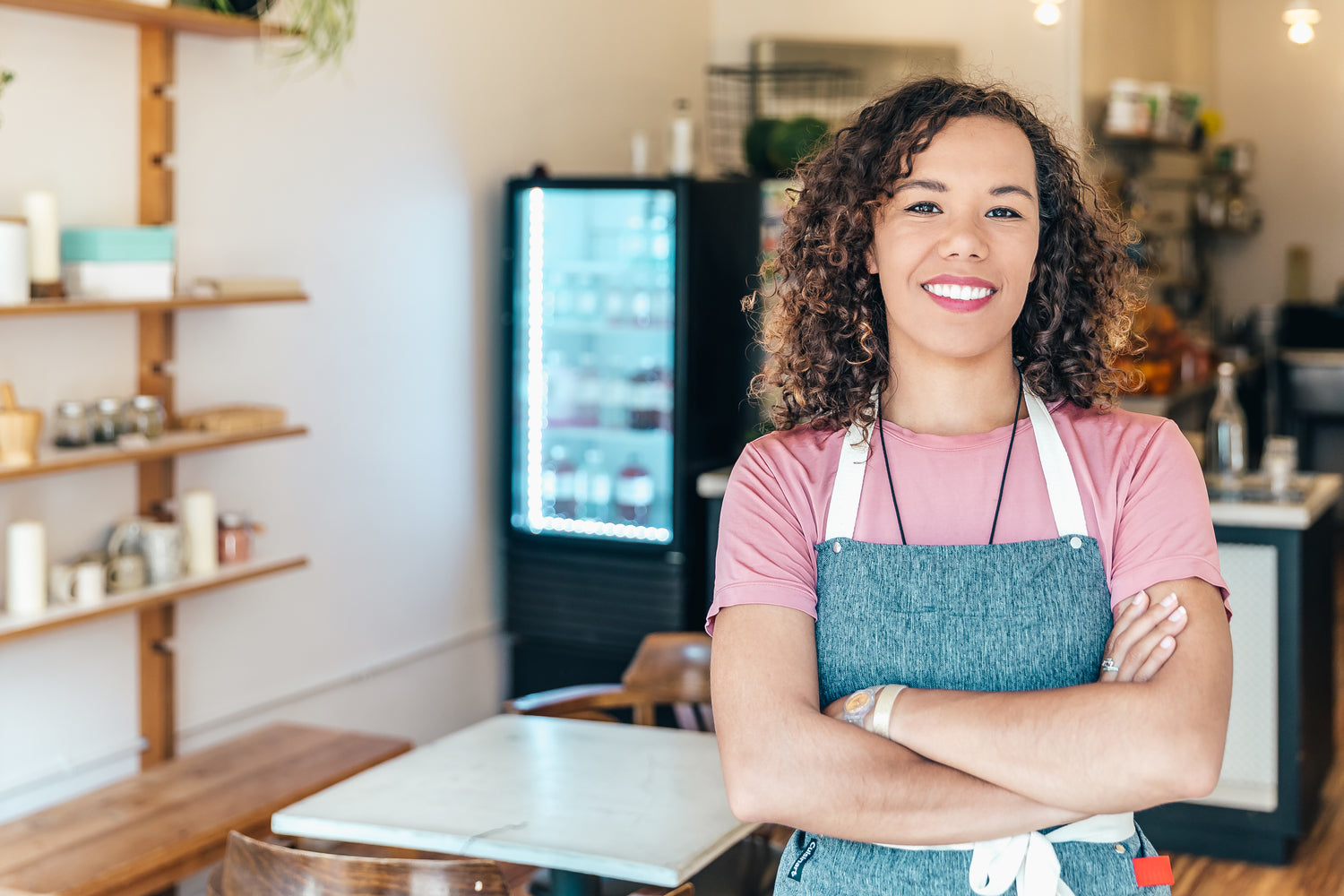 A BARISTA SMILES PROUDLY STOOD IN HER CAFE